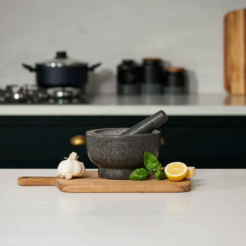 The Cole & Mason Clavering Pestle & Mortar is a dark gray granite set with the pestle inside the bowl—an essential, traditional kitchen tool ideal for home chefs.