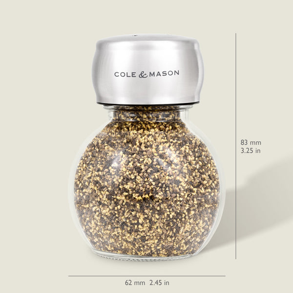 The Darlington Shakers Set by Cole & Mason features a glass and stainless steel spice grinder for seasoning control, filled with pepper granules, measuring 83 mm tall by 62 mm wide; Cole & Mason is labeled on the top. Dimensions shown right and bottom.