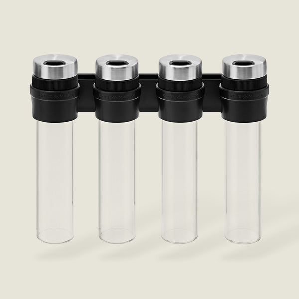 The Cole & Mason Shadwell Slim-Mount Spice Storage features four clear airtight glass containers with silver lids in a vertical black wall rack—ideal for stylish herb and spice storage.